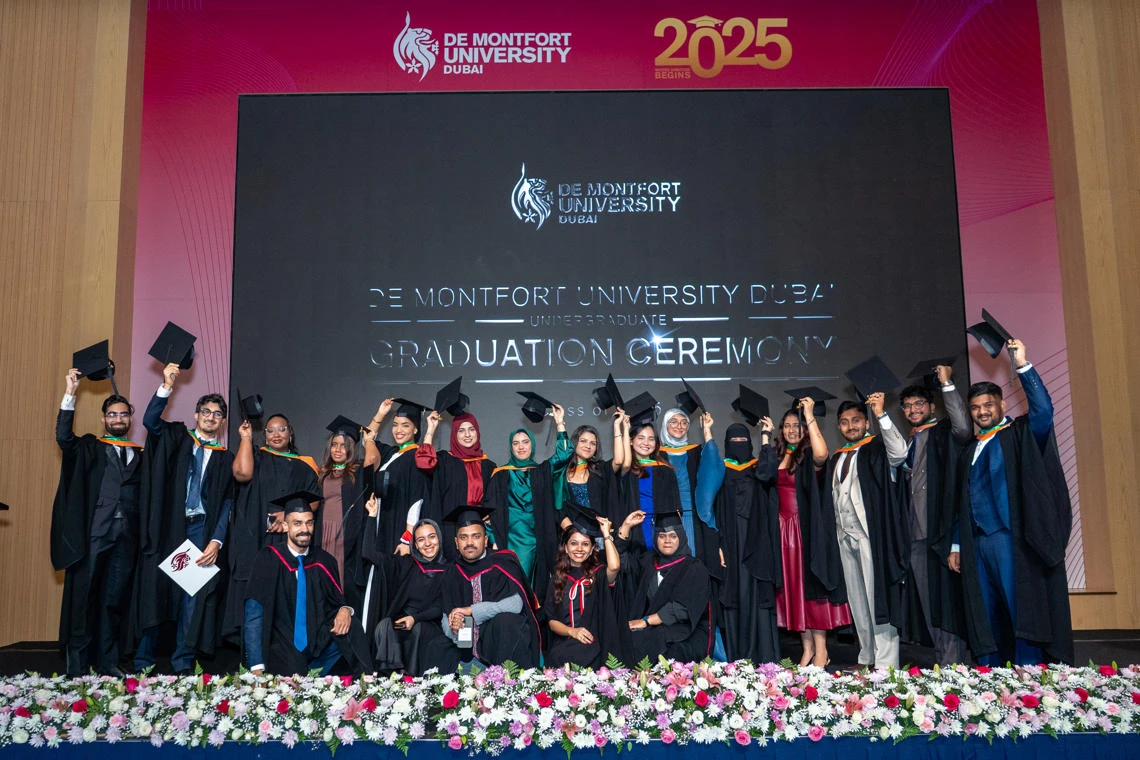 DMU Dubai students celebrate on stage at their graduation ceremony
