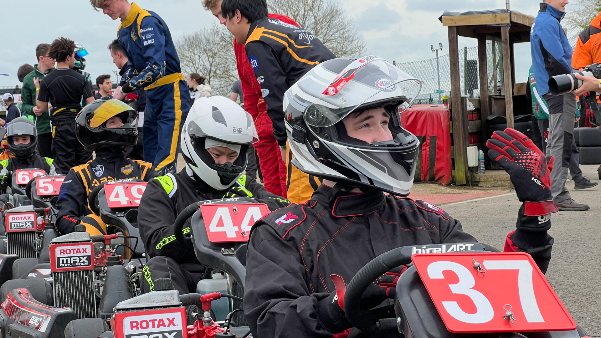 People in helmets and racing suits seated in go-karts, preparing for a race.