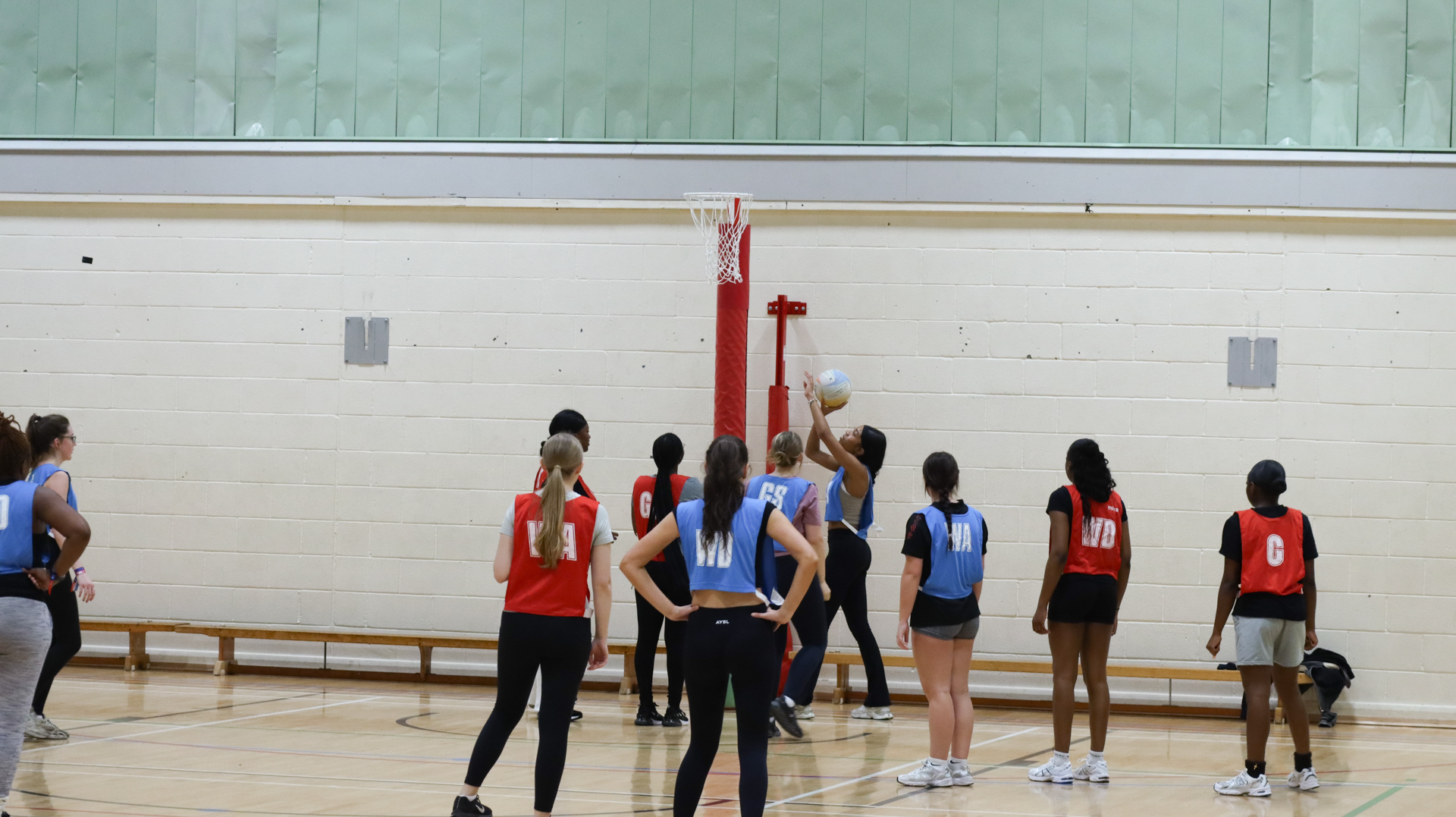 People wearing red and blue bibs playing netball.
