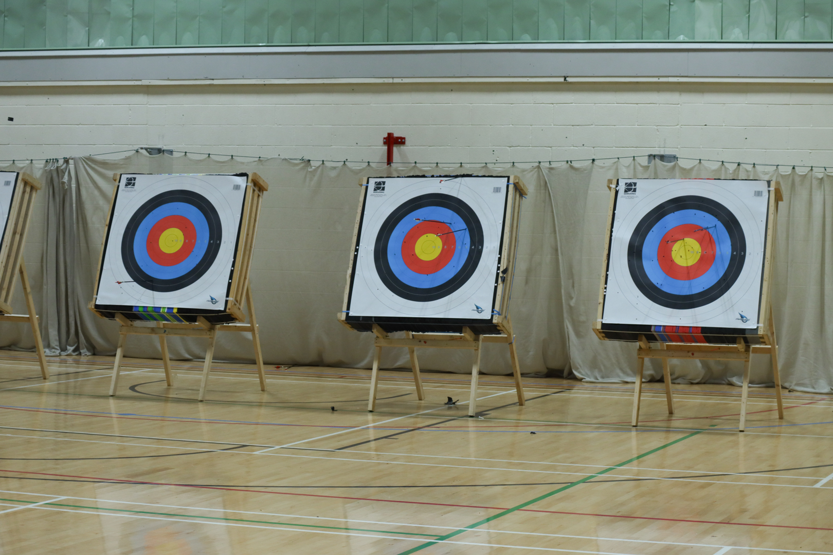 Three archery targets with concentric colored rings set up indoors on stands at the Watershed.