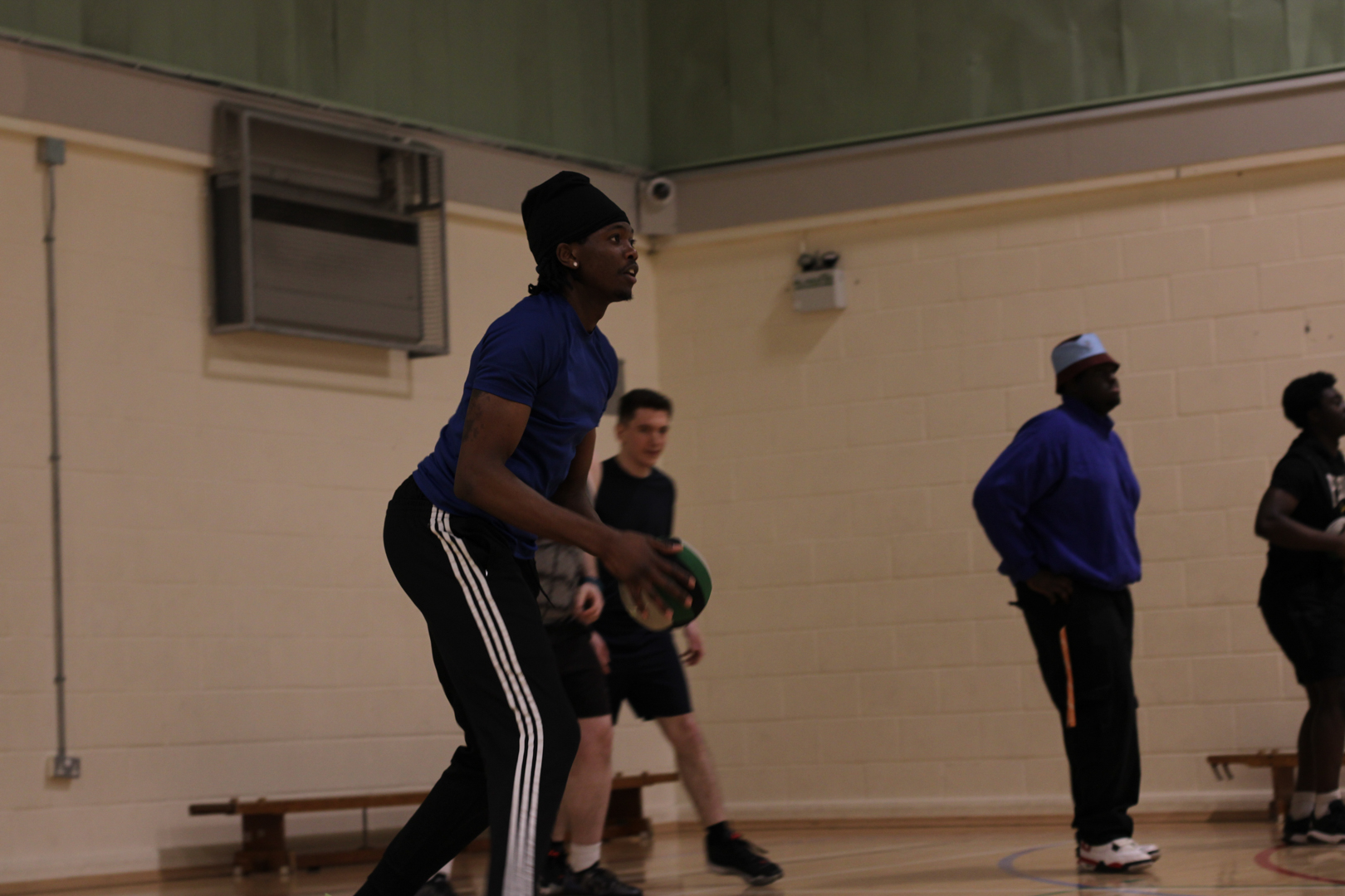 Several people in a gymnasium, with one person holding a Dodgeball. 