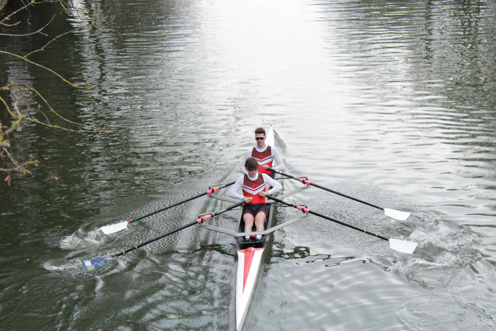 Two people in a rowing boat paddling on a calm river.