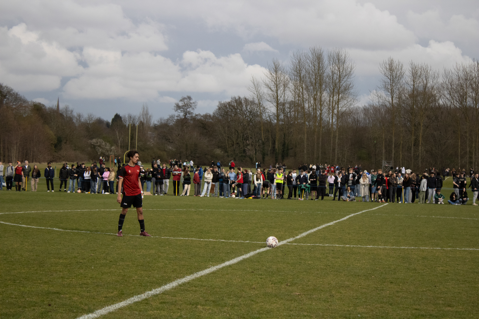 Football player preparing for a corner kick with spectators lined up along the field.