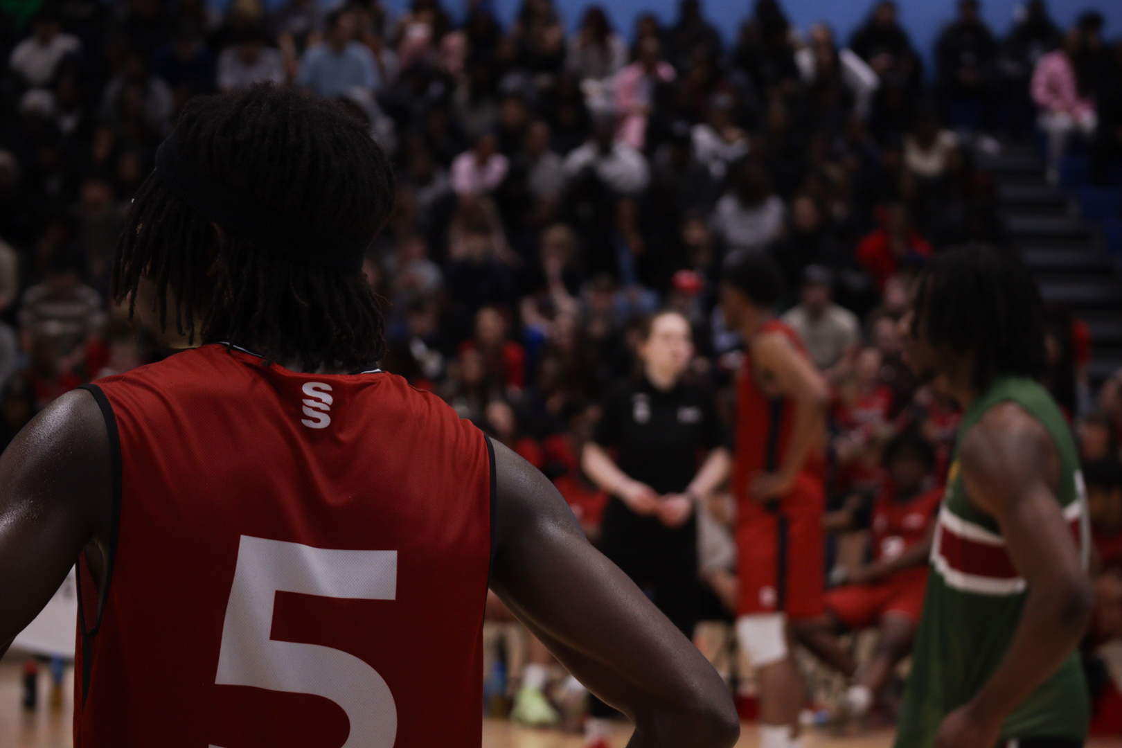 Basketball players in action on a court with a crowd of spectators in the background.