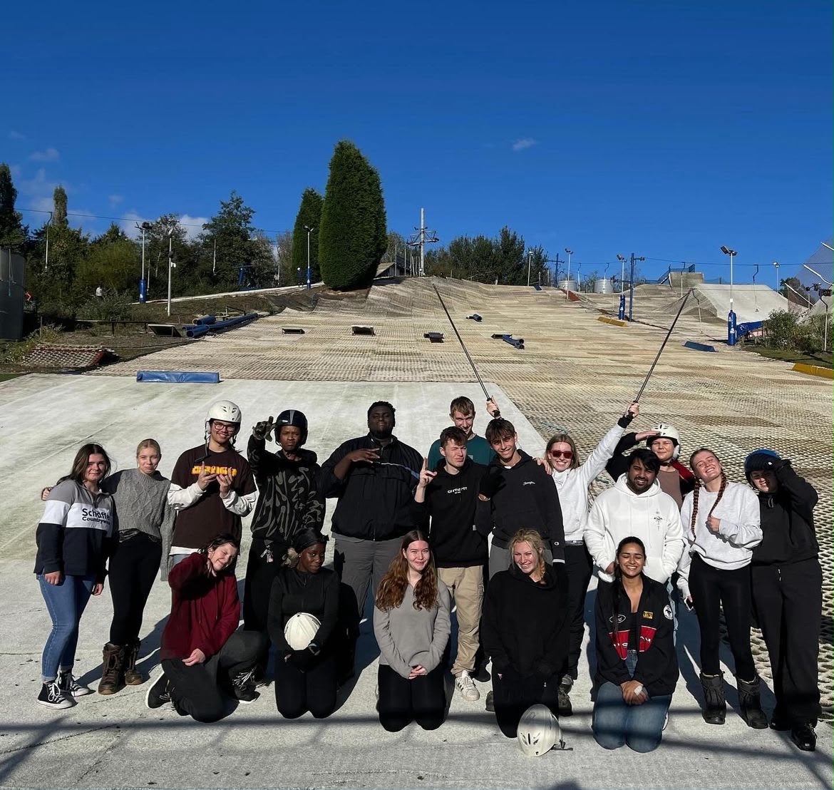 A group of people posing together outdoors on a large artificial ski slope.