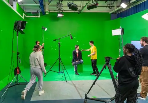 Students prepare to film a scene against a green screen background