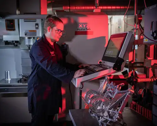 A student under red lighting using machinery