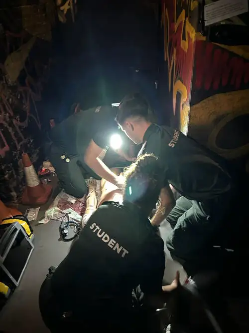 Students in a simulated darked alleyway off campus with an advanced manikin