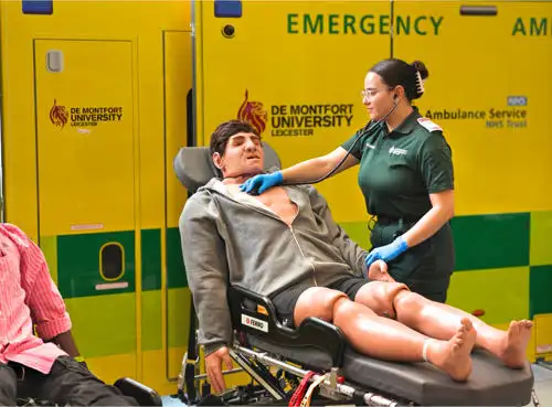 Student in uniform practising clinical skills with manikin on stretcher