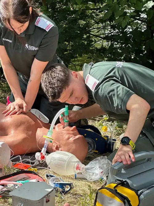 Students practising advanced life support outside on campus with a lifecast manikin