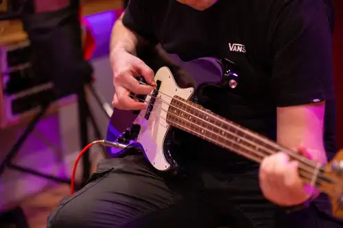 Person playing an electric guitar in a room with purple lighting.