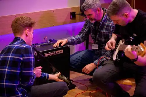 Students and a technical members of staff in a live recording studio where instruments and audio can be patched through to the control rooms.