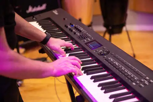 Person playing a digital keyboard or synthesizer in a music studio setting.
