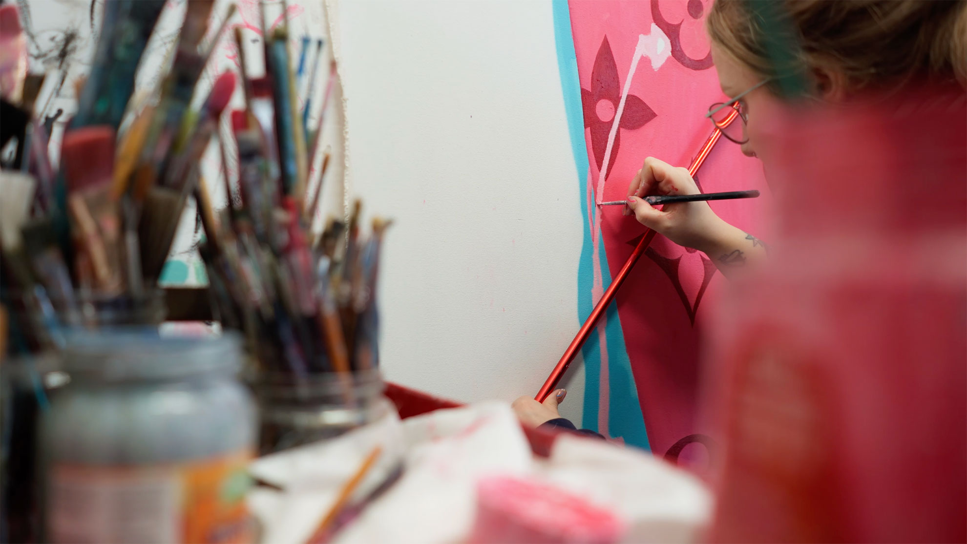 Video still of a woman painting pink flowers
