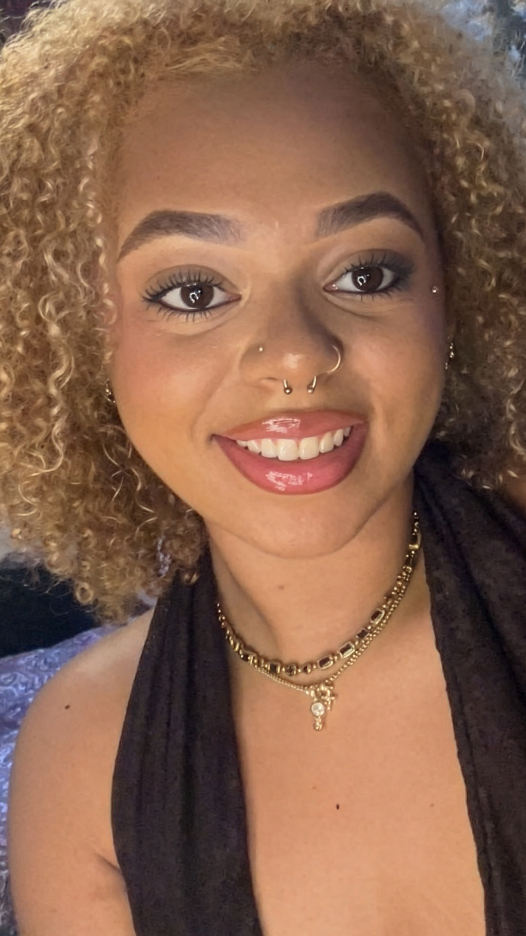 Smiling woman with curly blonde hair wearing a black halter top.