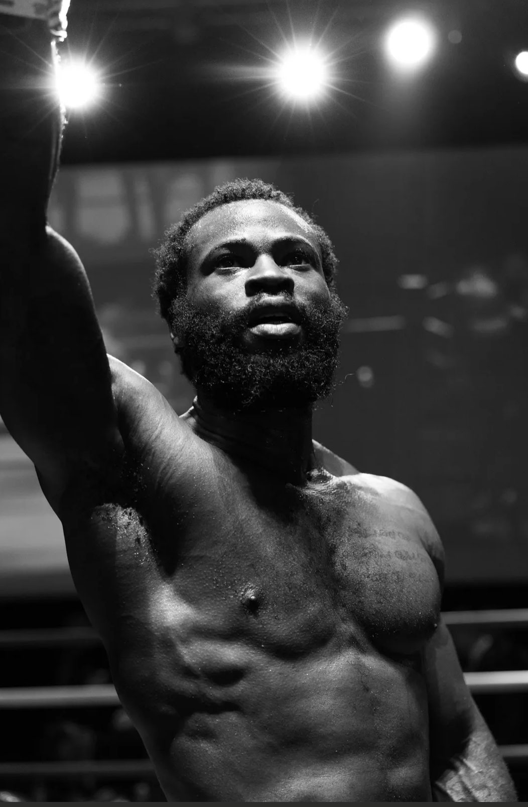 Black and white photo of a man in a boxing ring with one arm held up