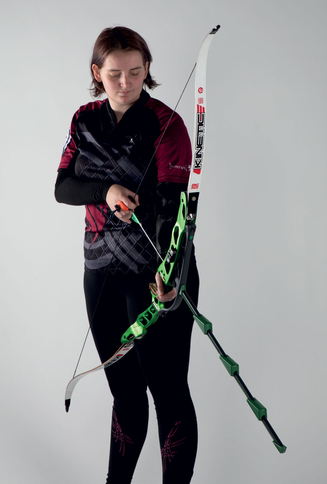 A student holding a black and green archery bow designed by Millie Rees