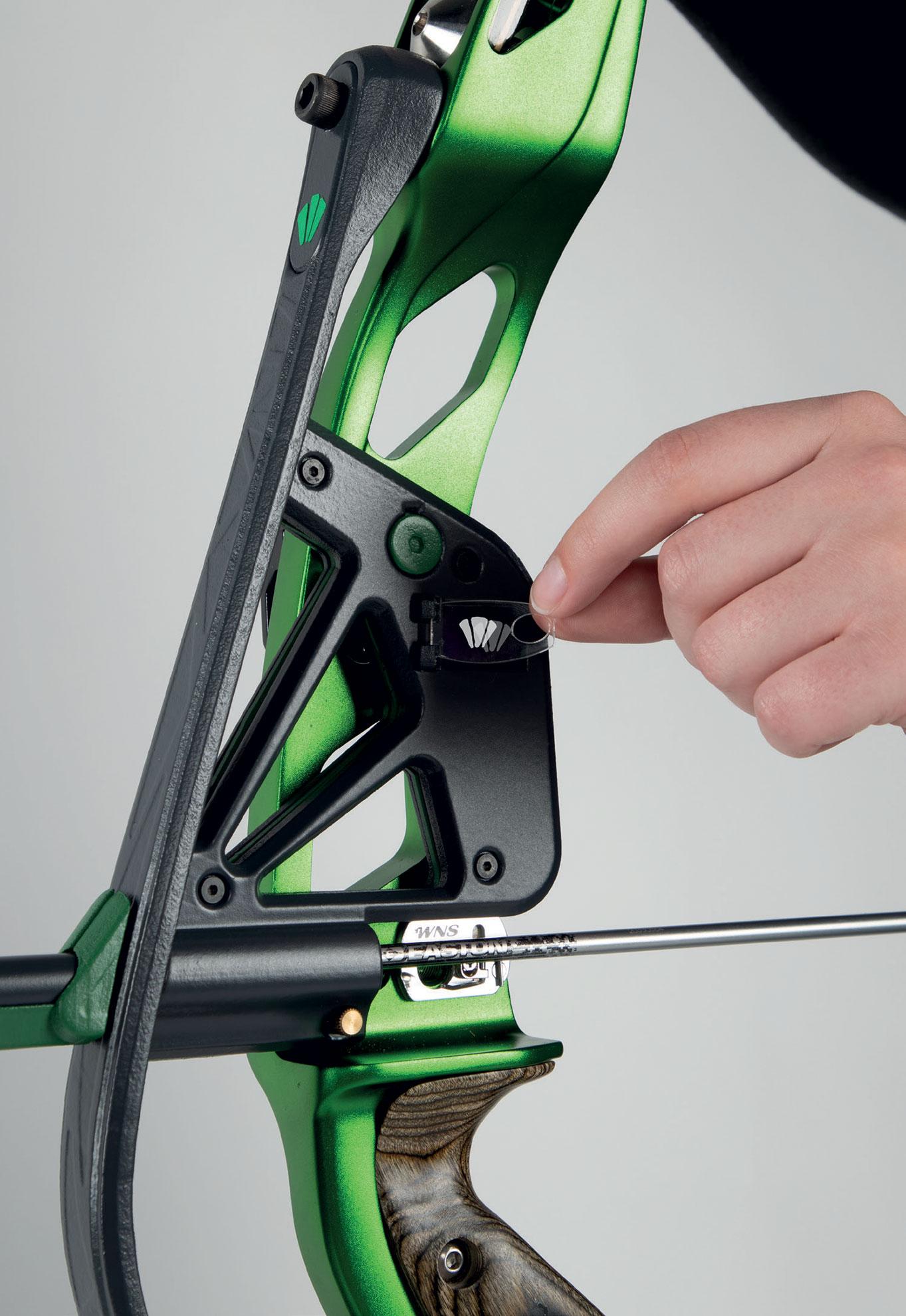 Closeup of a green metal component of an archery bow designed by Millie Rees