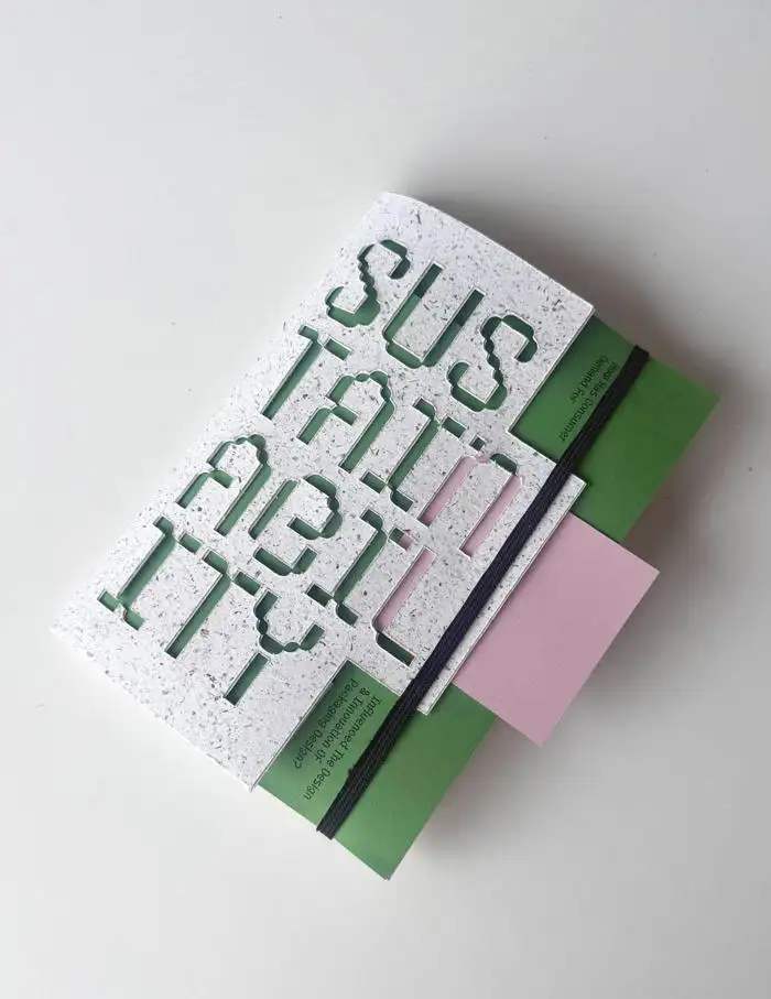 Book with the word "SUSTAINABILITY" on the cover, featuring green and pink geometric accents.