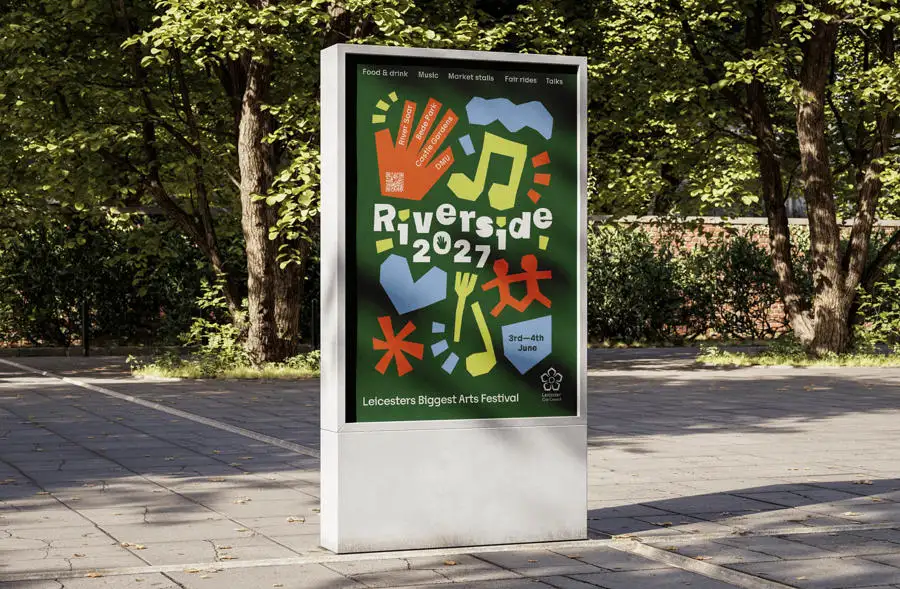 Colourful outdoor poster with music notes, a hand, a face, and abstract shapes on a green background, set in a park area.