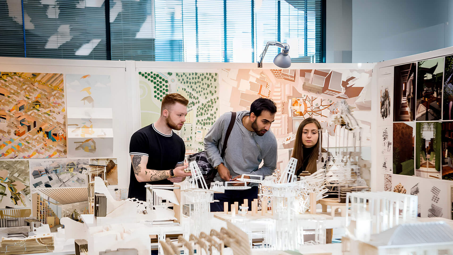 Three students examining and discussing various items displayed on a table.