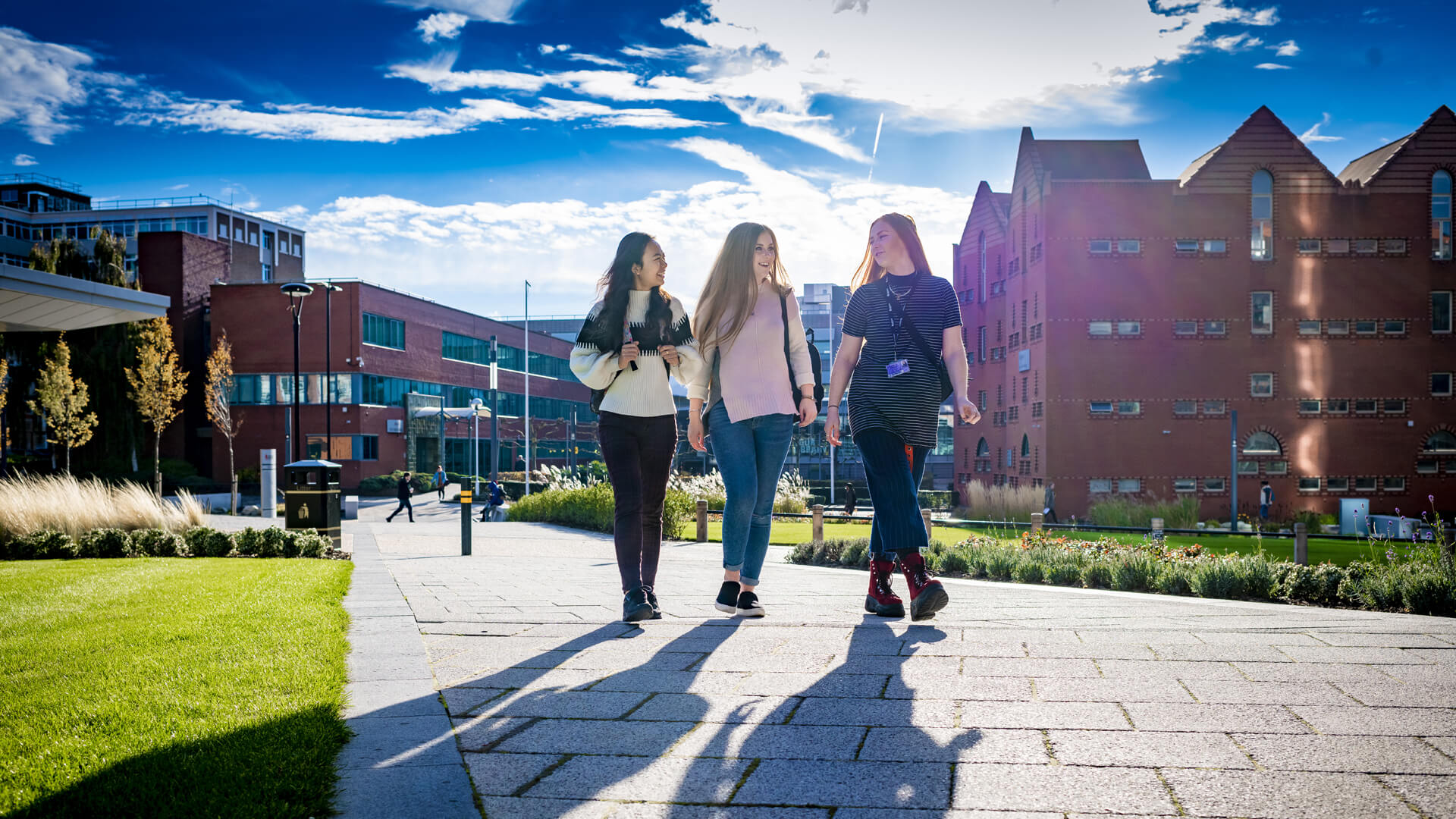 Three students walking on campus on a sunny day