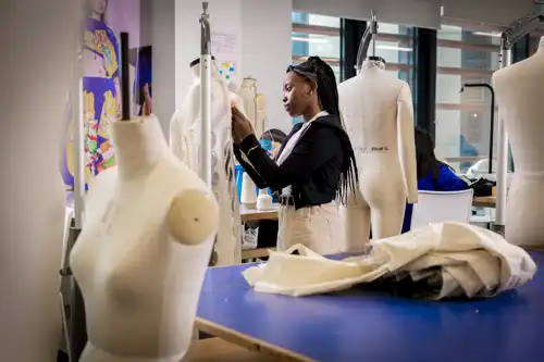 Fashion and Textiles student adjusting fabric on a mannequin
