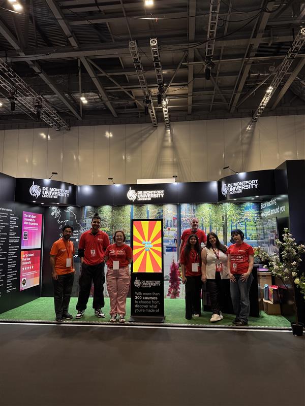 The DMU team standing at their stand at Excel London, smiling and ready to engage with students. 