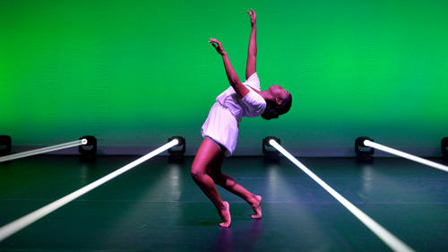 A dancer striking a dramatic pose against a green backdrop