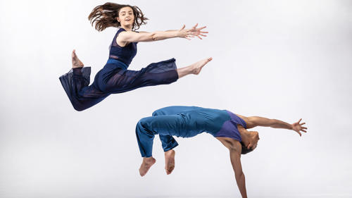 Two dancers in airborne poses on a white background