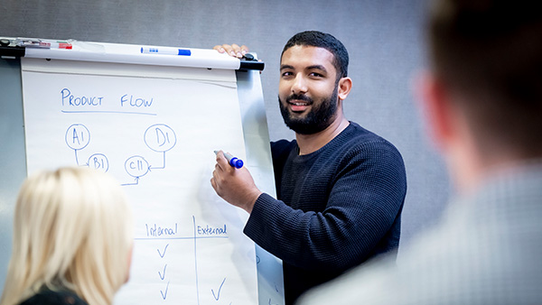 A photo of a male student in front of a flip board