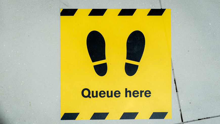 'queue here' sign on floor